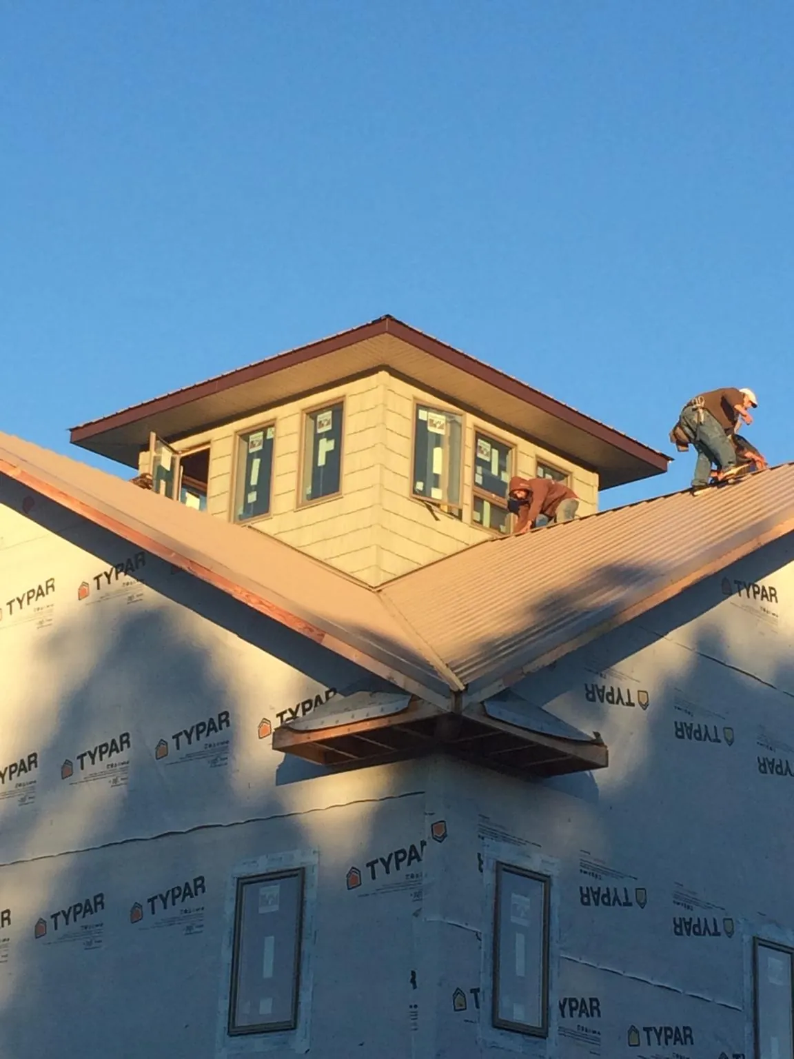 Roofers working around a rooftop cupola on a new metal roof at sunset — Roof Waterproofing in Ocoee by Roofing Brothers